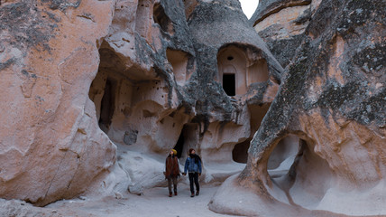Travel couple walking around rock formations in Pasabag Valley, the valley of the monks in Cappadocia, Happy couple standing near cave houses surrounded by fairy chimneys at Pasabag Valley in Turkey
