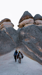 Travel couple walking around rock formations in Pasabag Valley, the valley of the monks in Cappadocia, Happy couple standing near cave houses surrounded by fairy chimneys at Pasabag Valley in Turkey