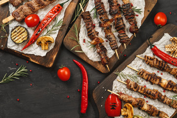 Grilled Lula kebab on skewers served on wooden board, black table background