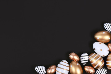 Golden, black and white easter eggs painted with stripes, hearts and dots in corner of black background with blank copy space