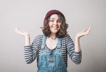 smiling woman in hat throws up his hands, wearing a jumpsuit
