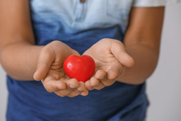 Little African-American boy with red heart, closeup. Concept of donations