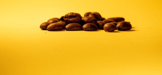 Arabica coffee beans, lying on the yellow gradient texture table