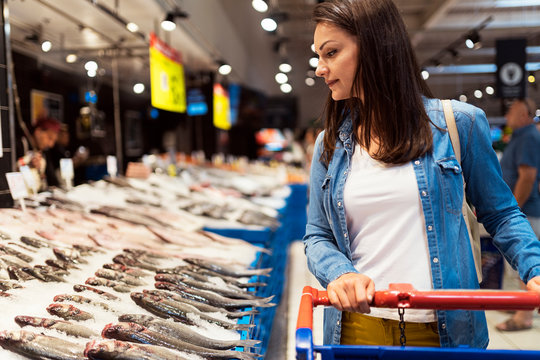 Beautiful woman buying fish in a fish shop