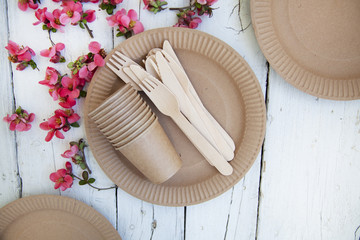  disposable eco tableware from paper cardboard spoon fork knife on a white wooden table, top view.