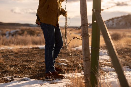 Rancher Fixing Barbwire Gate during Sunrise