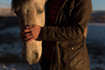 Ranch hand checking on horses in Winter at Sunrise