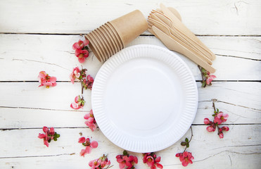  disposable eco tableware from paper cardboard spoon fork knife on a white wooden table, top view.