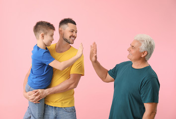 Man with his father and son giving high-five to each other against color background
