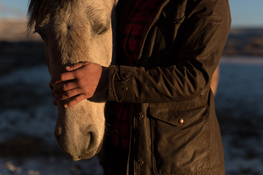 Ranch hand checking on horses in Winter at Sunrise