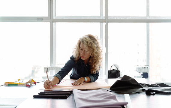 Woman drawing sewing pattern on paper
