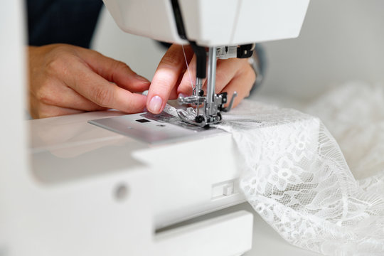 Crop woman sewing lace fabric