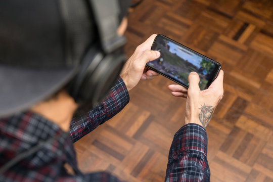 Close up of a man hand paying a mobile game at home. Smart phone, blurred screen 