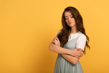 Obraz premium attractive tender girl with crossed arms on yellow