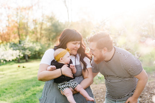 stock photo of young family playing with baby girl in the tree blossoms