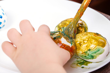 Children are preparing for Easter. Coloring eggs with brushes and multi-colored paints