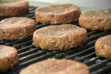 Raw hamburger patties sitting on hot char broiler grill