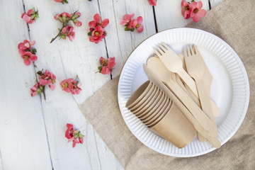  disposable eco tableware from paper cardboard spoon fork knife on a white wooden table, top view.
