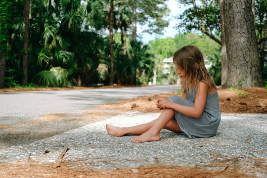girl sits quietly in driveway