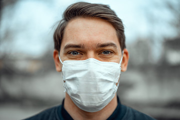 Portrait man in medical mask. Young man stands on light background and looking at camera.