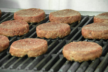 Raw hamburger patties sitting on hot char broiler grill