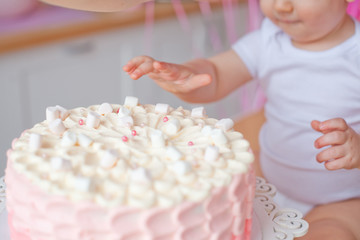 little girl on the table with a birthday cake and balloons