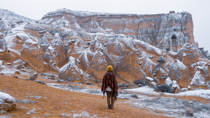 Woman alone with the volcanic landscape at Devrent Valley in Cappadocia. Girl walking around Fairy chimneys surronded by tufa formations at Imaginary Valley in winter season in Cappadocia, Turkey.