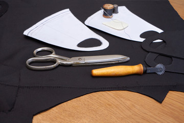 Process of making medical facial mask at home with sewing kit, black mask onwooden table, layout of...