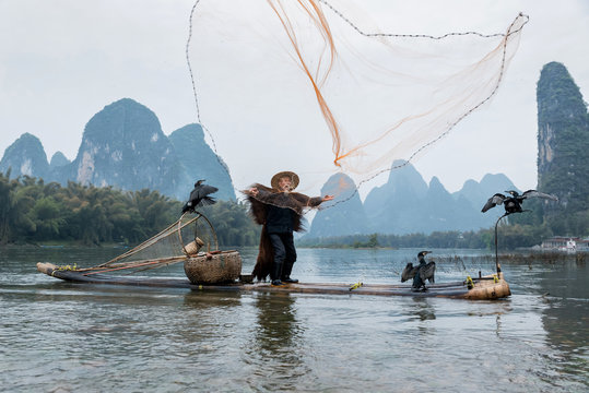 Fisherman throwing fishing net in river while standing on raft