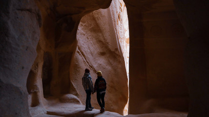 Travel couple standing into the cave surrounded by rock formations at Zelve Valley in Cappadocia, Turkey