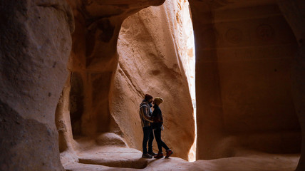 Travel couple standing into the cave surrounded by rock formations at Zelve Valley in Cappadocia, Turkey
