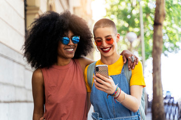 Beautiful lesbian couple using a mobile in the Street