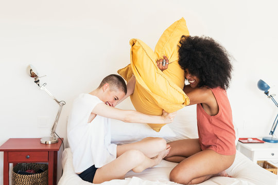 Young couple playing with pillows in bedroom