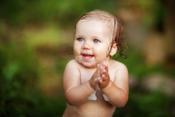 baby bathes in a basin on the street in the summer, flying water splashes, happy child
