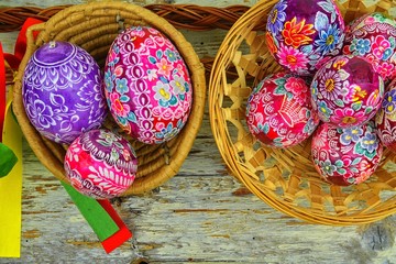 Still life with Easter eggs. Decorated Easter eggs lay in a wicker basket on a white wooden...