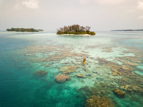 Aerial view of two-man paddling near Pulau Macan Island, Indonesia.