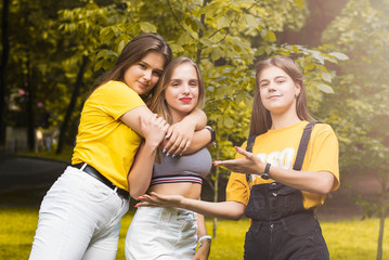 Three nice teen girls having fun in the park. Excellent sunny weather. Autumn concept. Hugging. Lifestyle. Trendy Hipster Girls