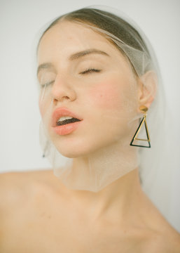 Portrait of a girl in a veil with triangle earrings who s ecstatic