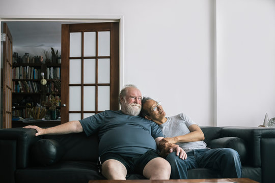 Portrait Of Loving Retired Senior Gay Couple Sitting Together At Home