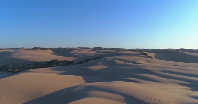 Beautiful 4k aerial video of sand dunes fly over with people walking at sunset