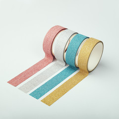 Four rolls of glitter tape and parallel strips on white background