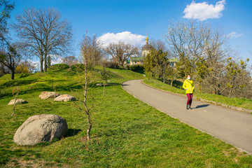 Obraz premium The young woman in the protective medical mask walks in the park on a sunny spring day.