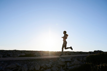 Silhouette of sportswoman running nature sunset.