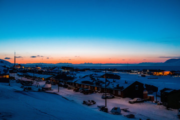 North snowy city against beautiful sunset