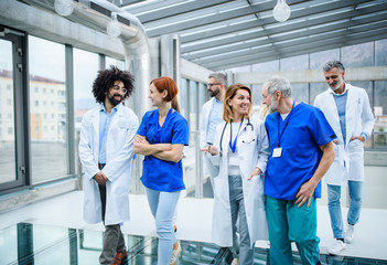 Front view of group of doctors walking in corridor on conference.