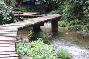  wooden bridge pathway a river in a mountain forest in Sichuan, China