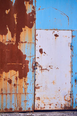 Multicolored background, rusty metal surface with blue paint flaking and metal door with padlock