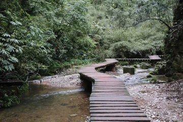 Raamstickers houten brugweg een rivier in een bergbos in Sichuan, China © salah