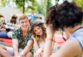 Group of young friends sitting on ground at summer festival.