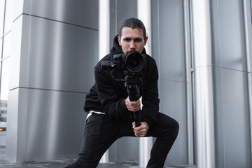 Young Professional videographer holding professional camera on 3-axis gimbal stabilizer. Pro...
